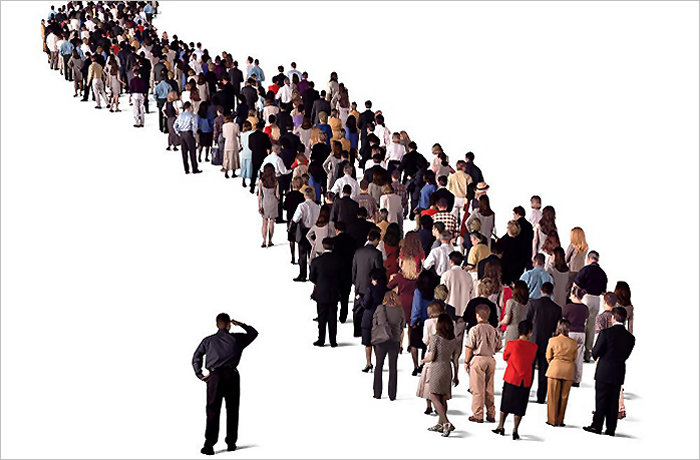 A long line of diverse people standing closely together, with one individual in the foreground appearing to look back thoughtfully.