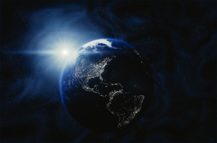 A view of Earth from space, illuminated by sunlight, with cities sparkling in the dark.
